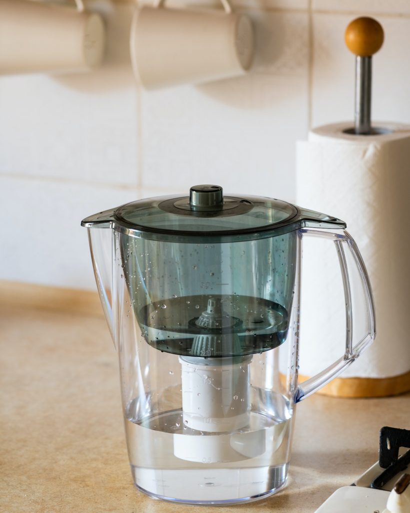 Water filter jug on kitchen table. Clean water concept. Filtration water